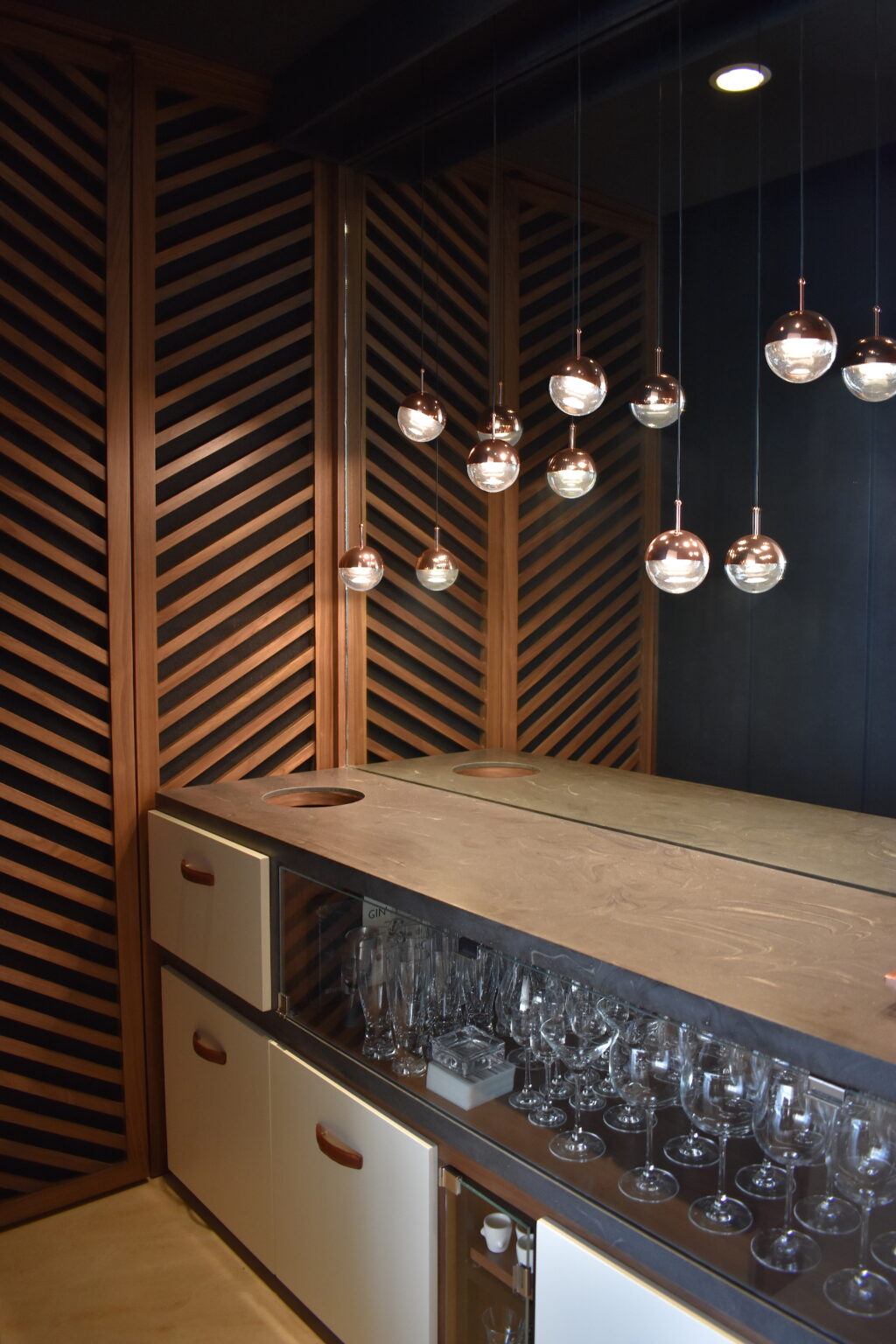 Mueble de bar con cajones, cristalería y paneles de madera en espiga