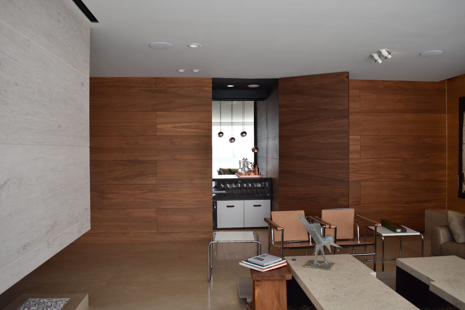 Sala residencial con panel de madera abierto que revela el bar Veramonte