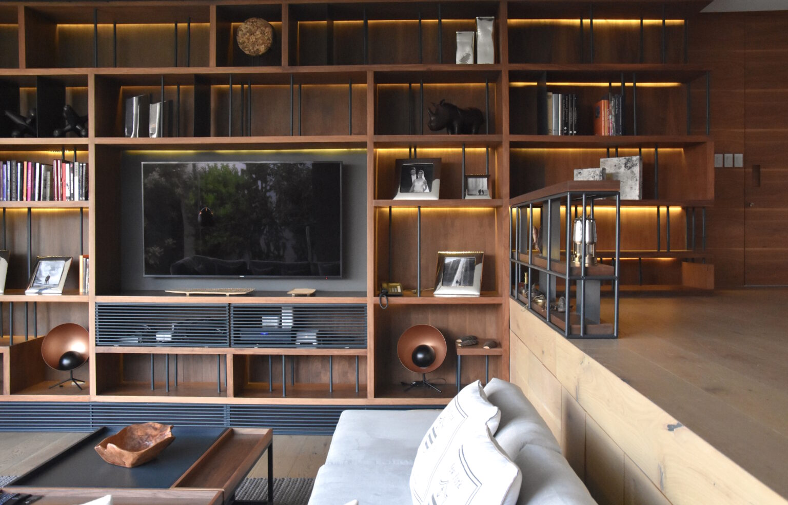 Sala de Bosques 83 con librero de madera iluminado y mueble para televisión
