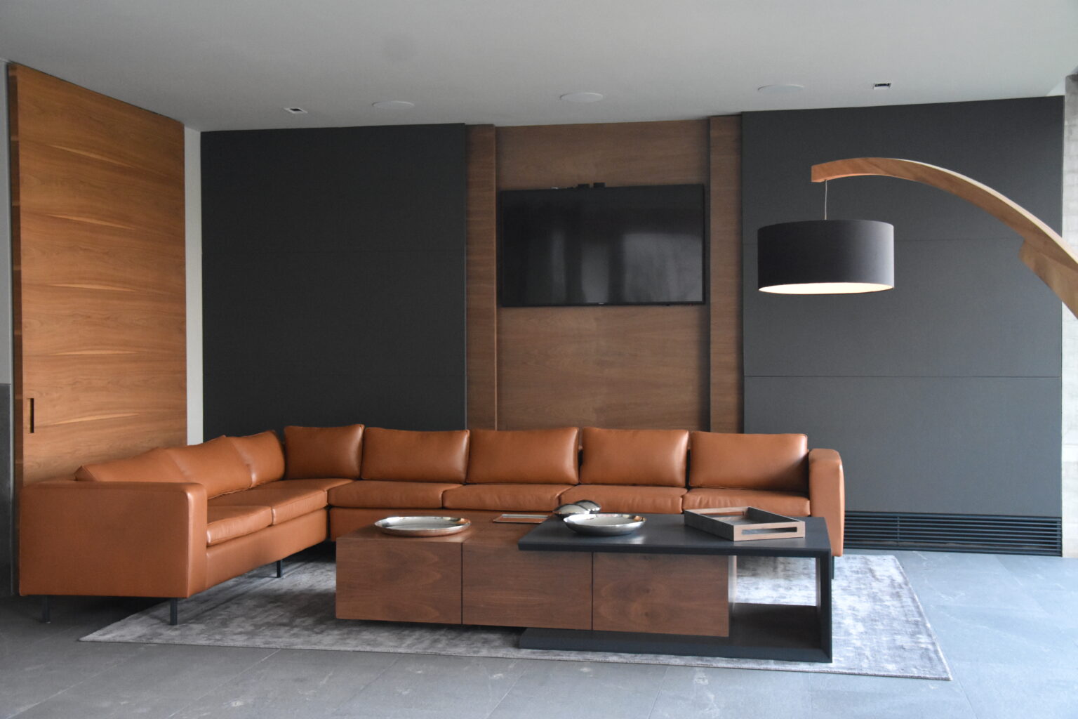 Sala de Bosques 83 con sofá seccional de piel café y muro para televisión