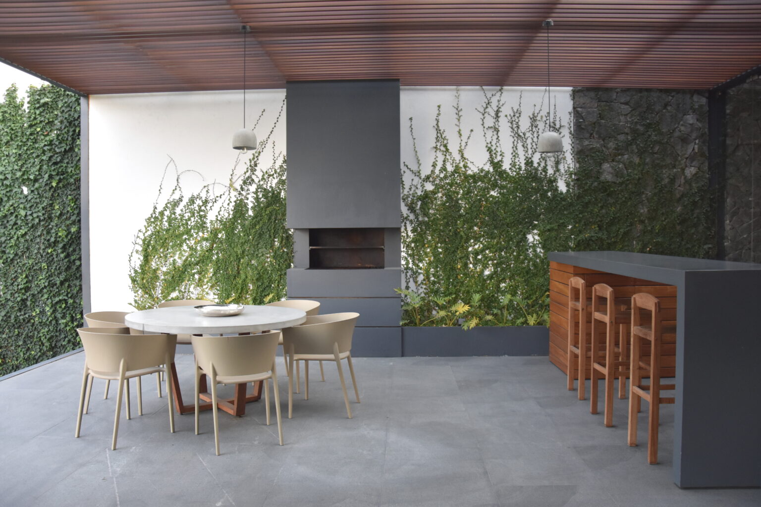 Terraza de Bosques 83 con comedor circular, chimenea y barra de madera