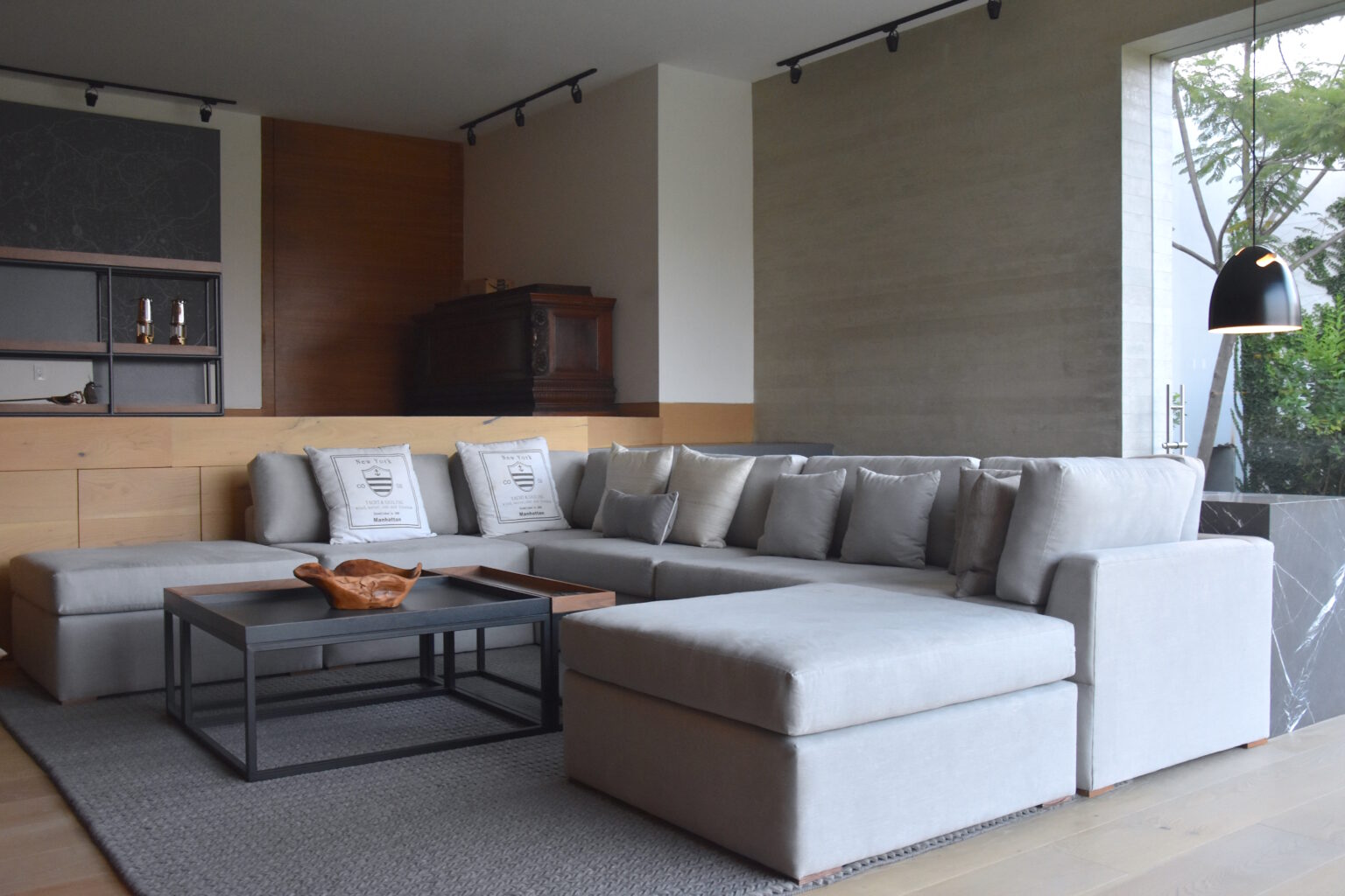 Sala familiar de Bosques 83 con sofá gris, mesa metálica y carpintería de madera