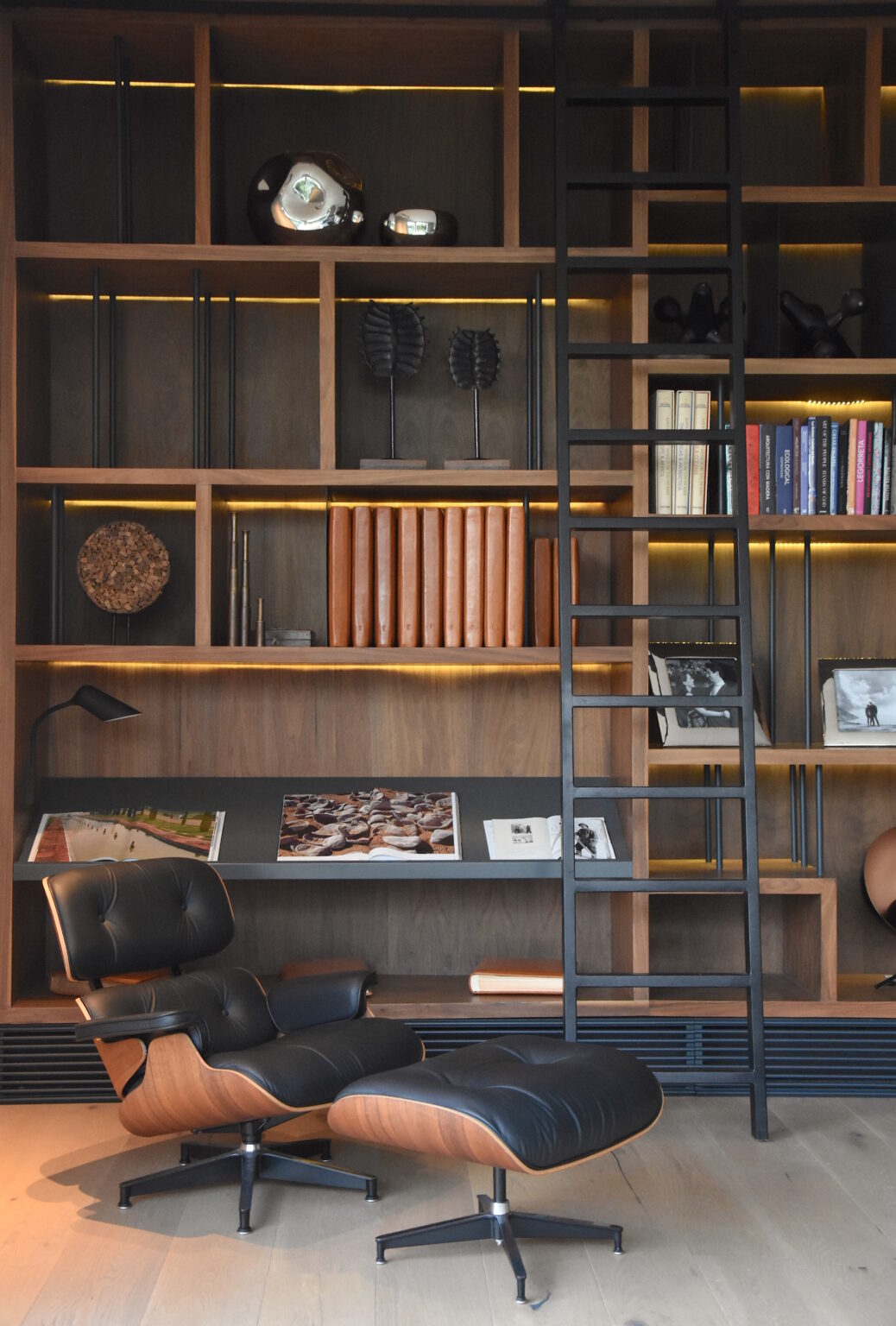 Biblioteca de Bosques 83 con librero iluminado, escalera y sillón lounge