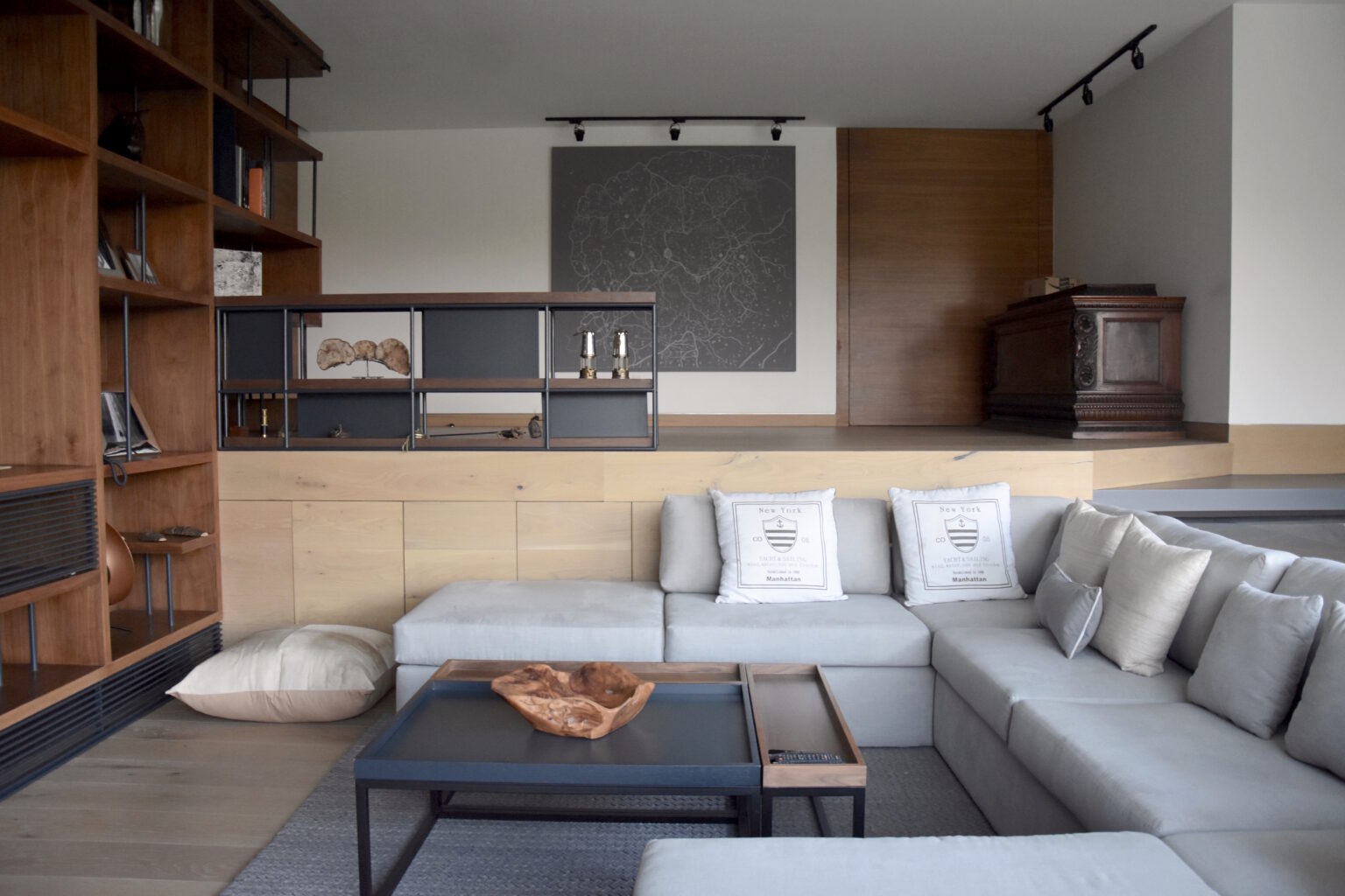 Sala de Bosques 83 con sofá gris y mobiliario de madera y metal a medida