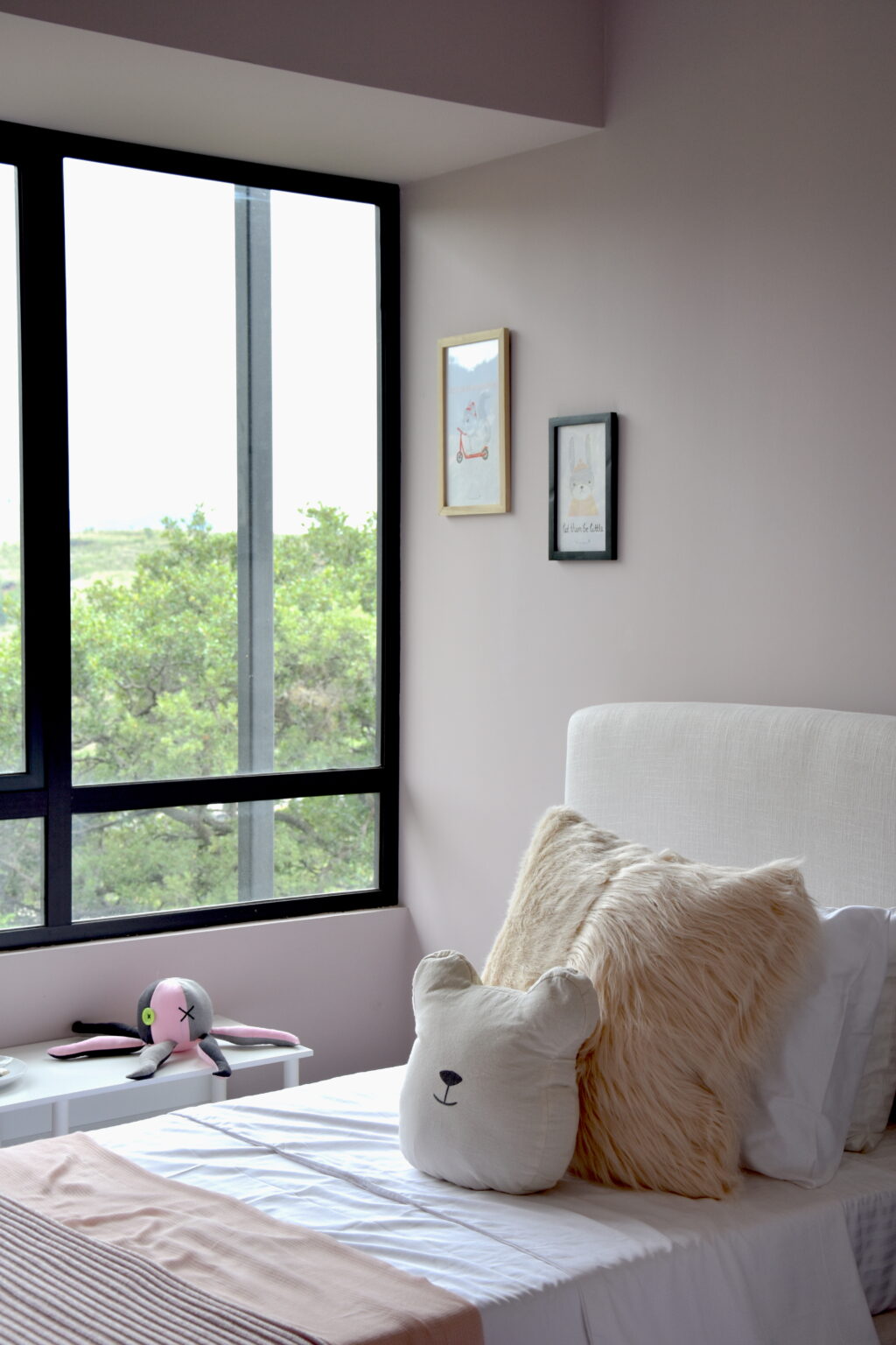 Recámara infantil rosa con cama tapizada y cojines decorativos en Real de Monteza