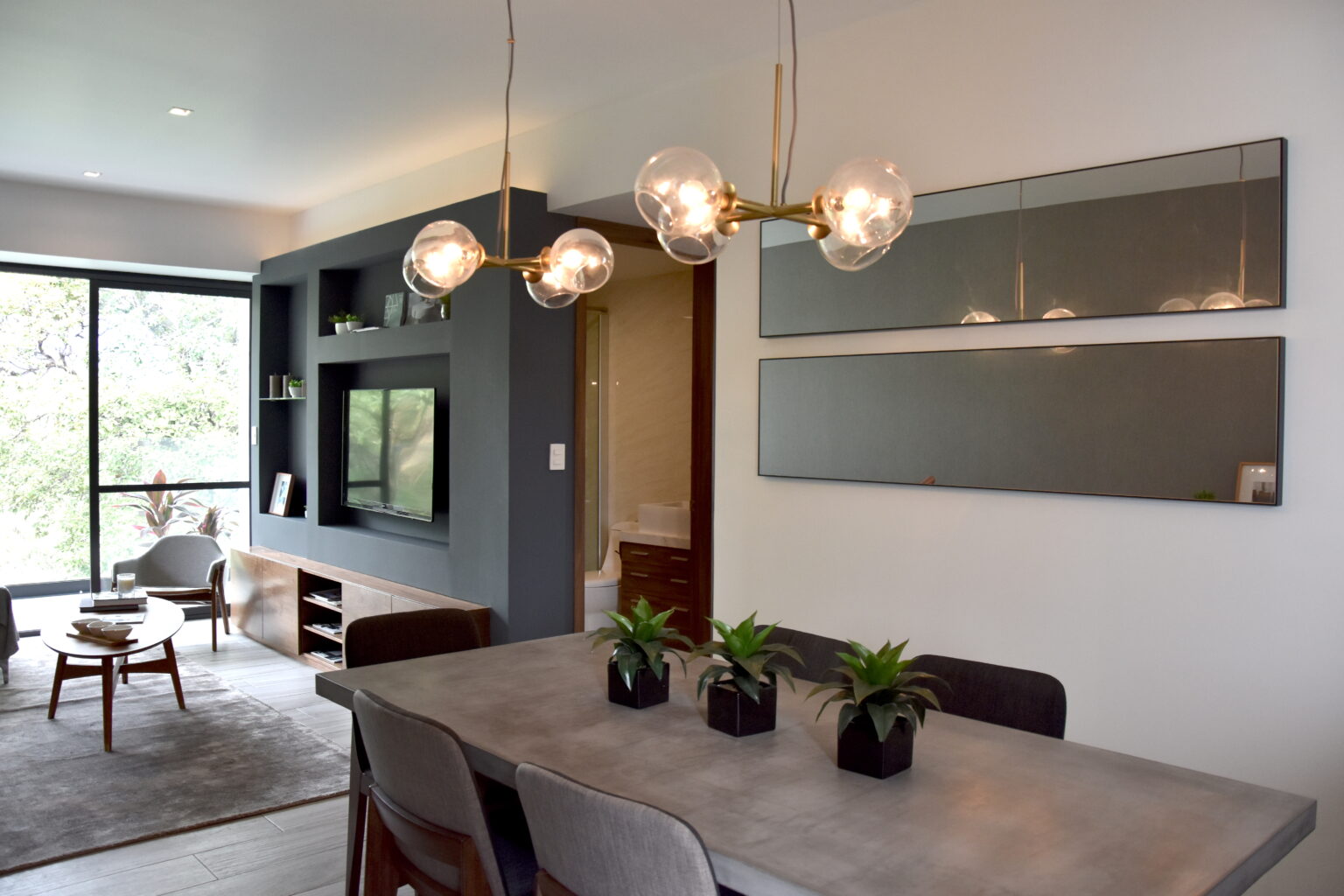 Sala y comedor integrados con mueble de televisión y luminarias de cristal en Real de Monteza