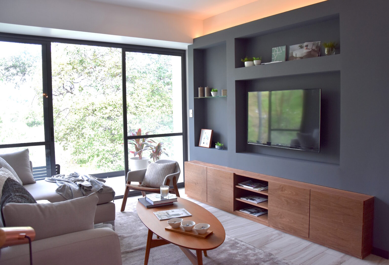 Mueble de televisión de madera con nichos grises en la sala de Real de Monteza
