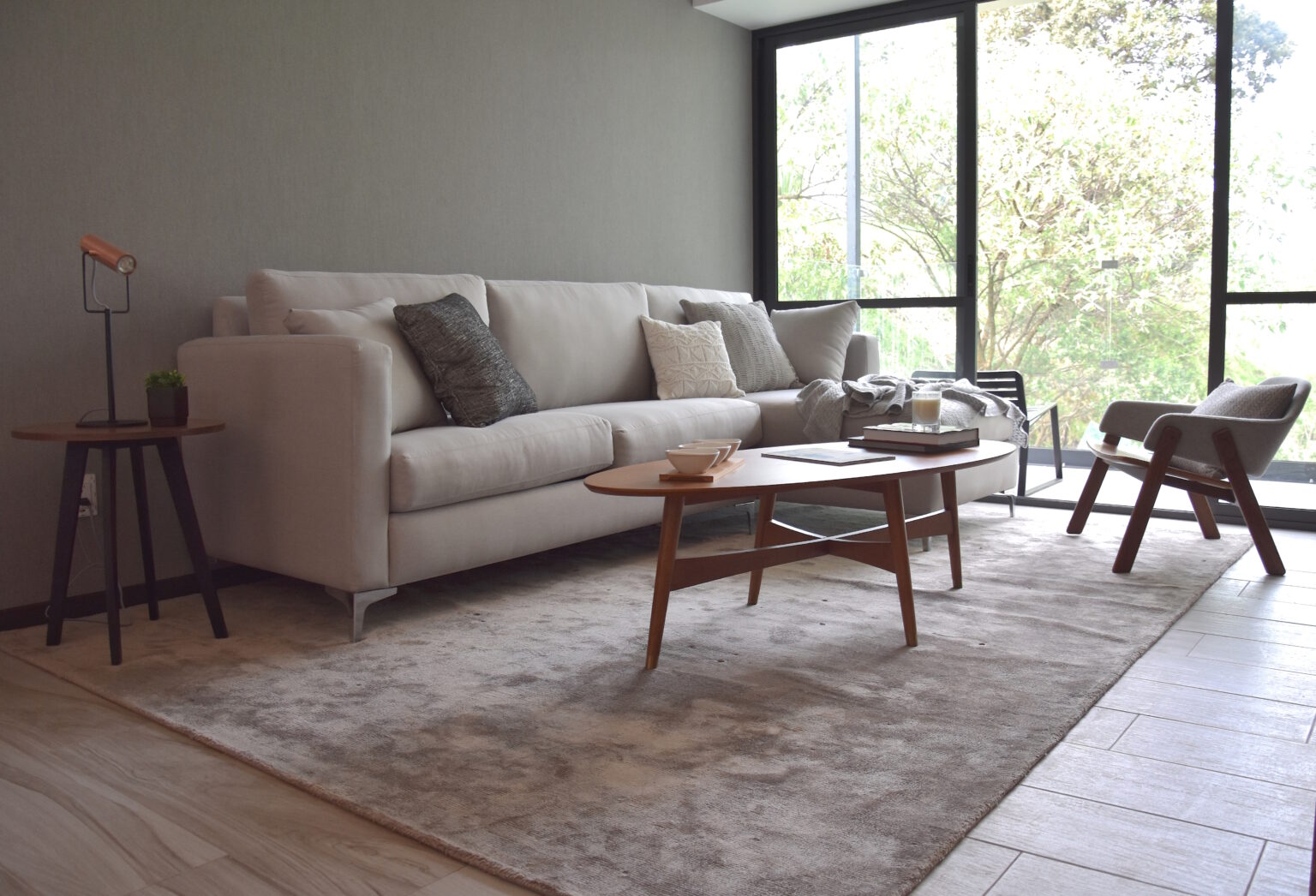Sala de Real de Monteza con sofá claro, mesas de madera y ventanal al bosque