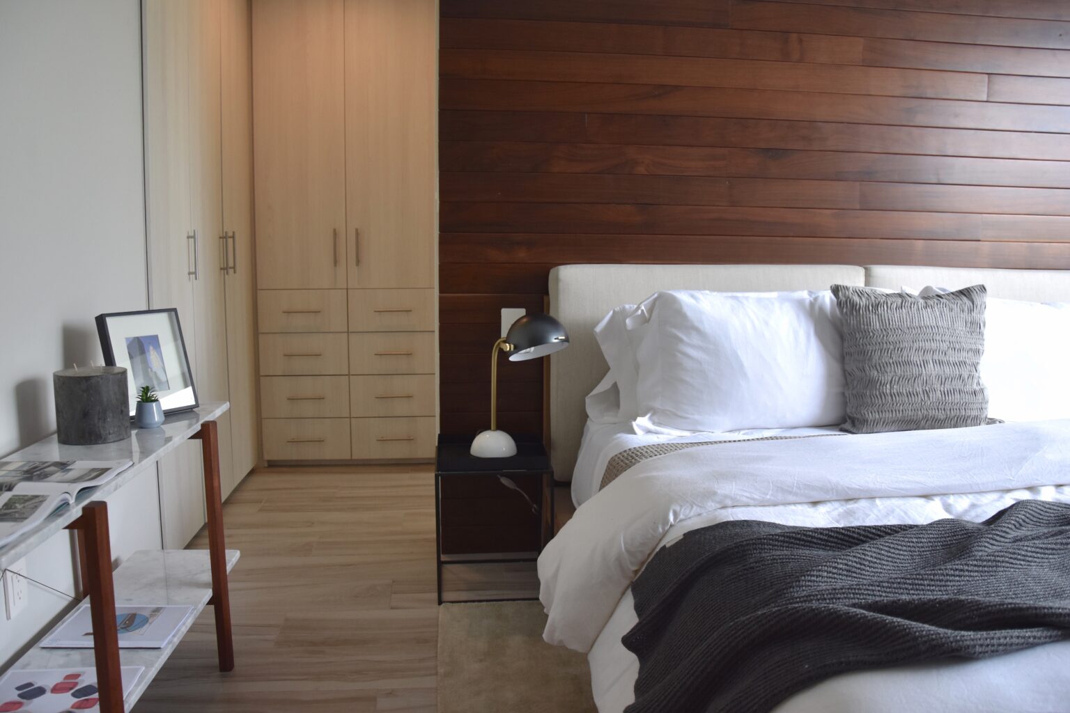 Recámara principal con muro de madera, clóset a medida y cama tapizada en Real de Monteza