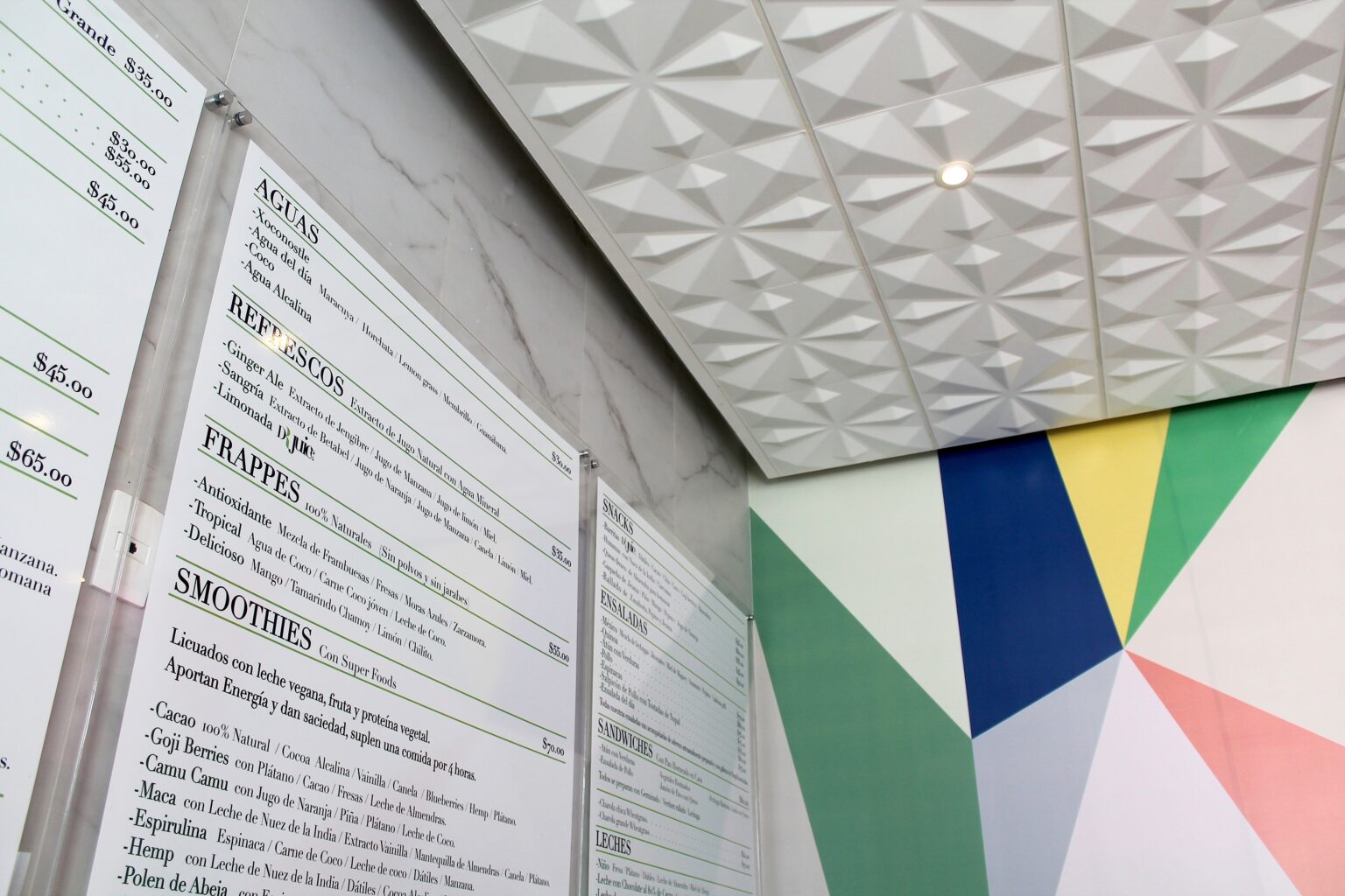 Menú mural junto a gráfica geométrica de colores y plafón tridimensional en Dr. Juice