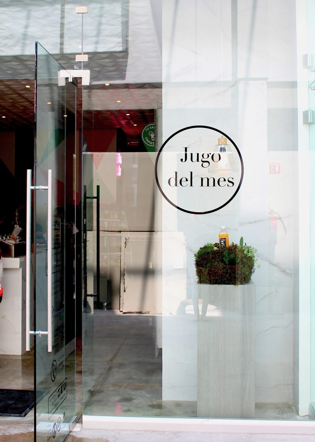 Acceso de cristal con señal de jugo del mes y jardinera suspendida en Dr. Juice
