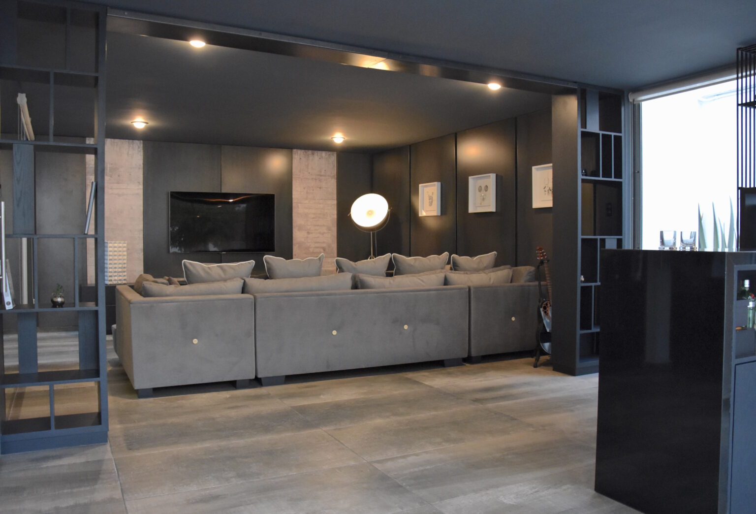 Family room con sofás grises, televisión y acceso al bar residencial