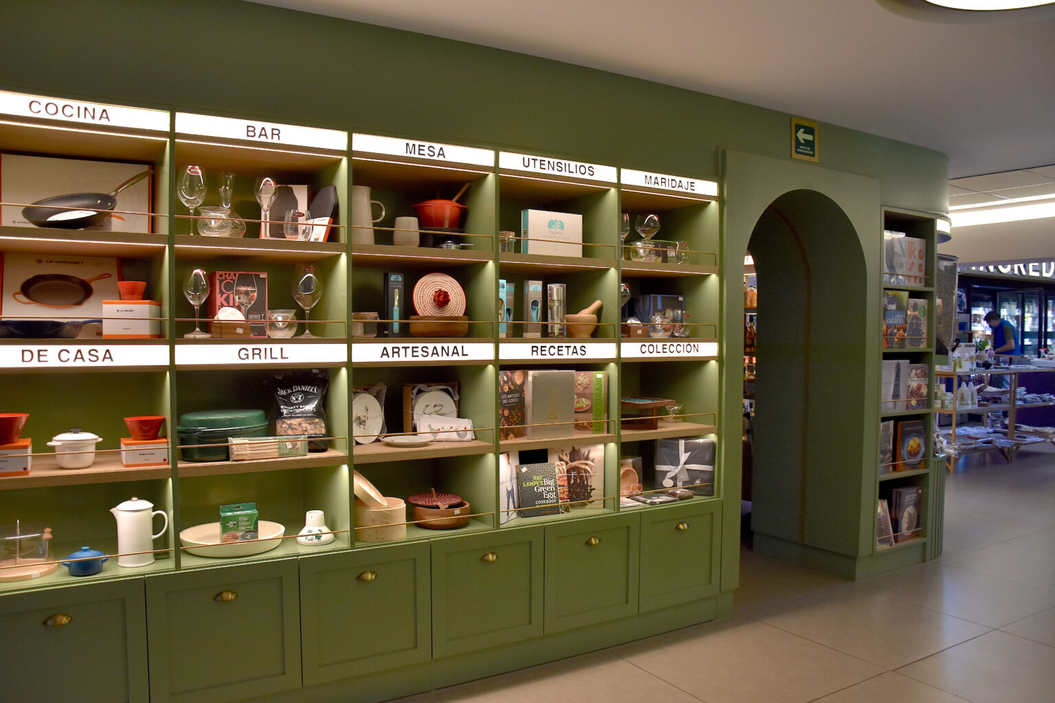 Muro verde de categorías con utensilios, vajilla y libros en Ingredienta Pedregal