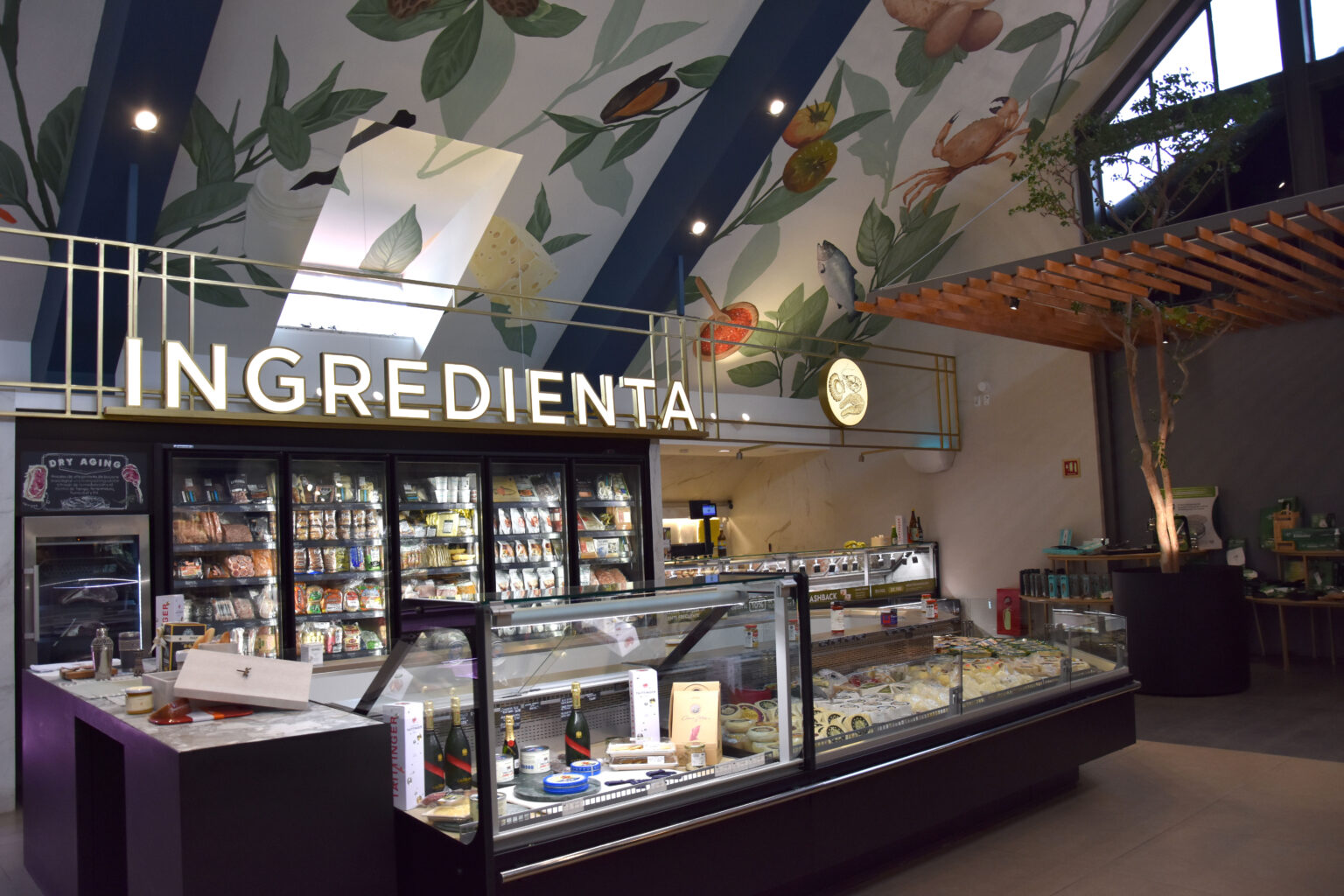 Vitrinas gourmet bajo el rótulo Ingredienta y mural botánico en Pedregal