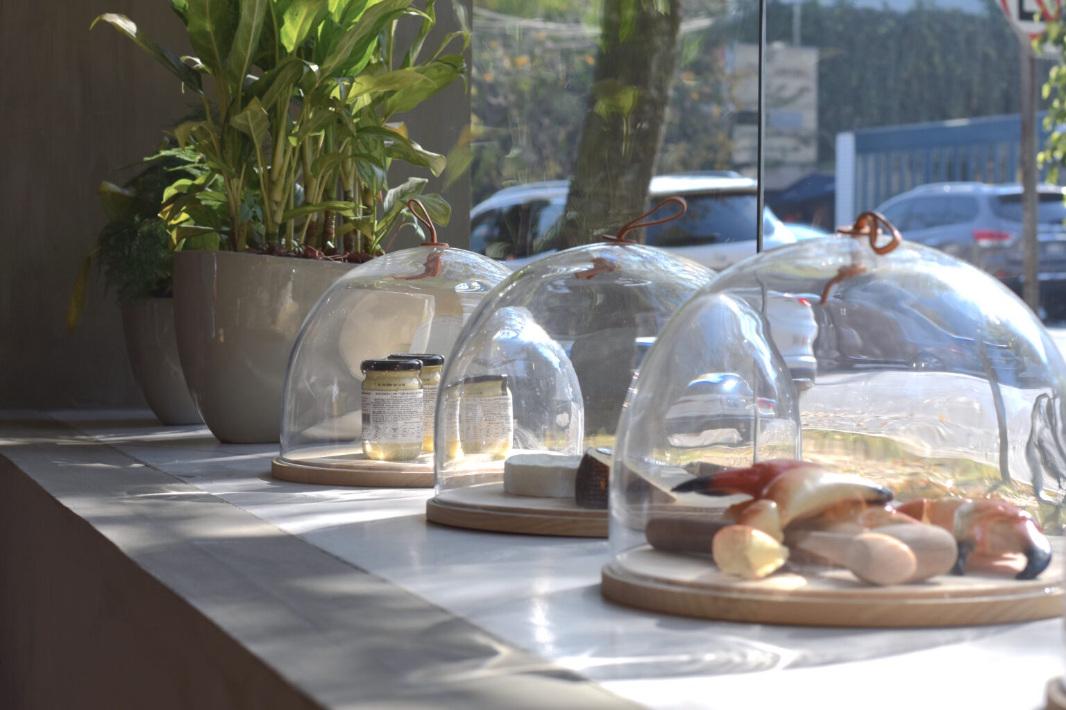 Productos gourmet bajo campanas de vidrio en el escaparate de Ingredienta Prado Norte