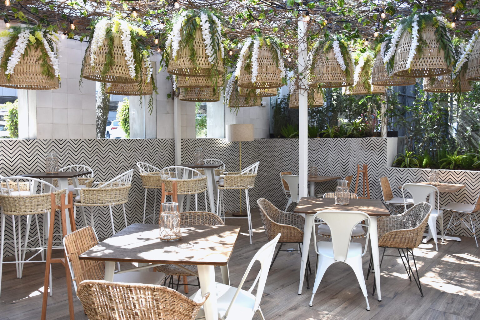 Terraza de Ingredienta Prado Norte con mesas, sillas tejidas y lámparas de mimbre
