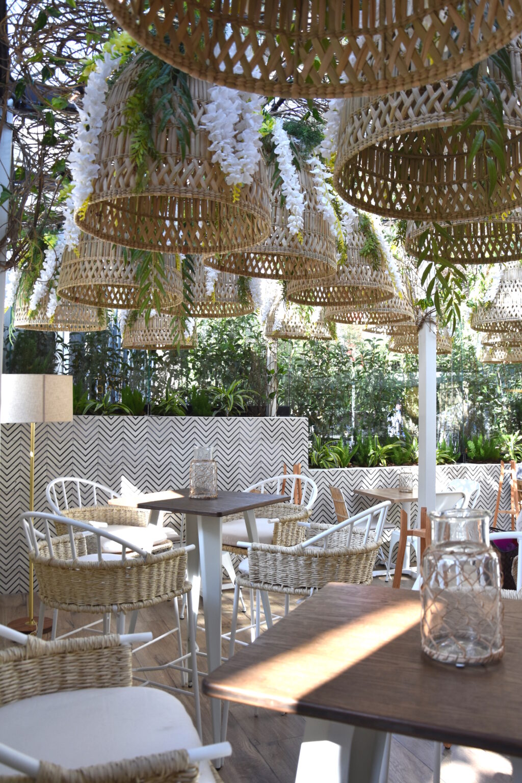 Comedor exterior de Ingredienta Prado Norte bajo lámparas de mimbre y vegetación