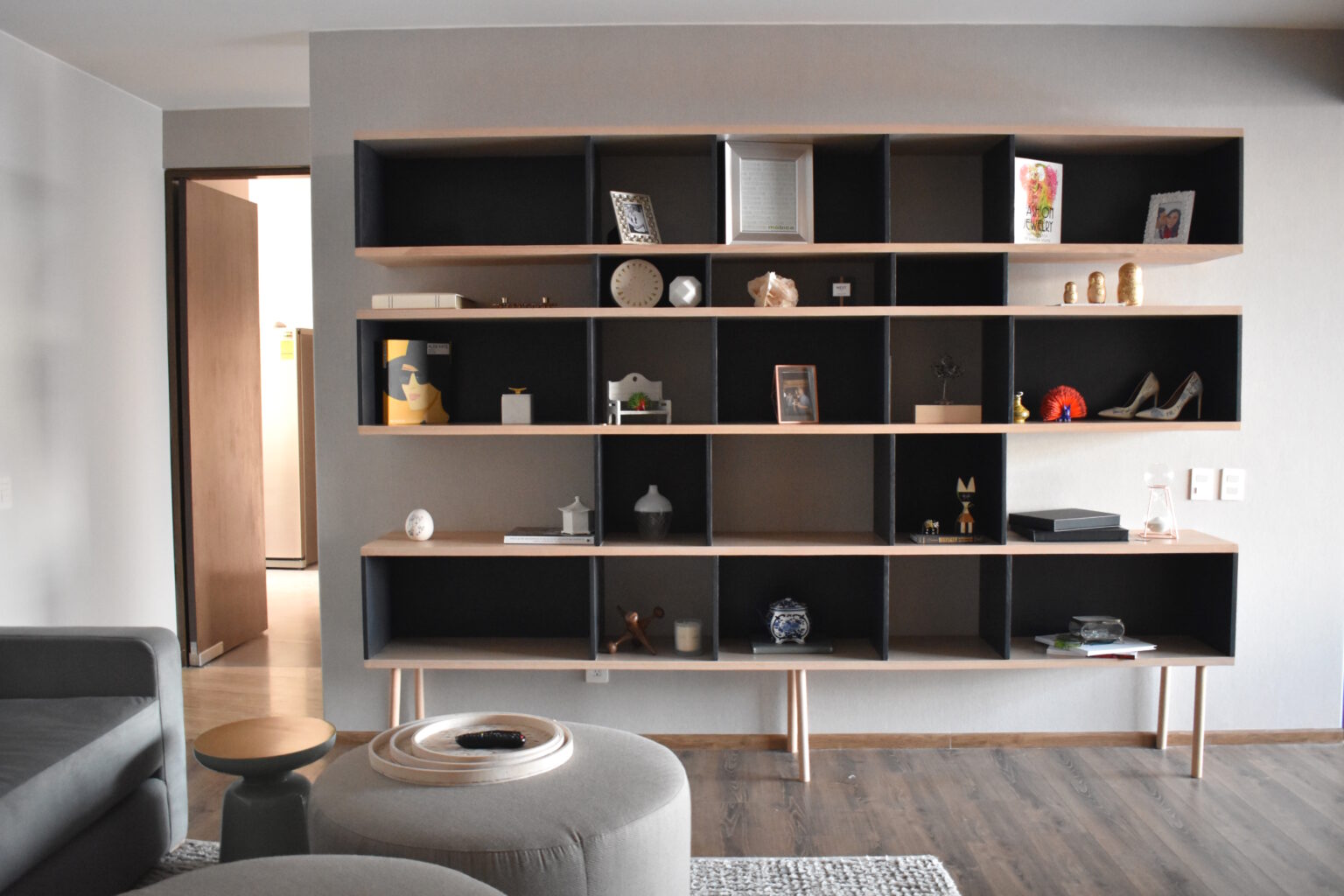 Librero modular negro y madera con objetos decorativos en la sala de Lo Alto