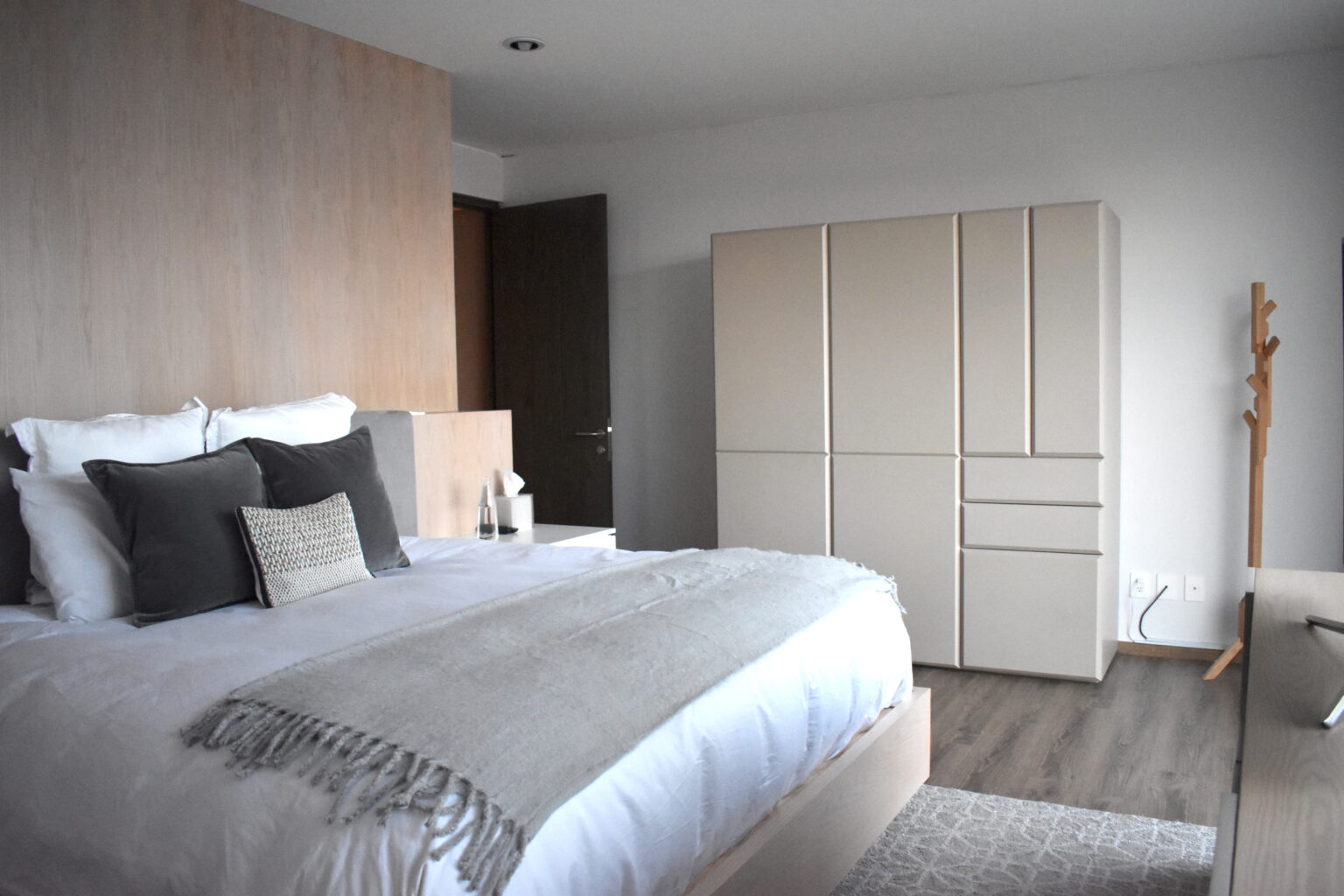 Recámara con cabecera de madera, cama gris y armario geométrico en Lo Alto