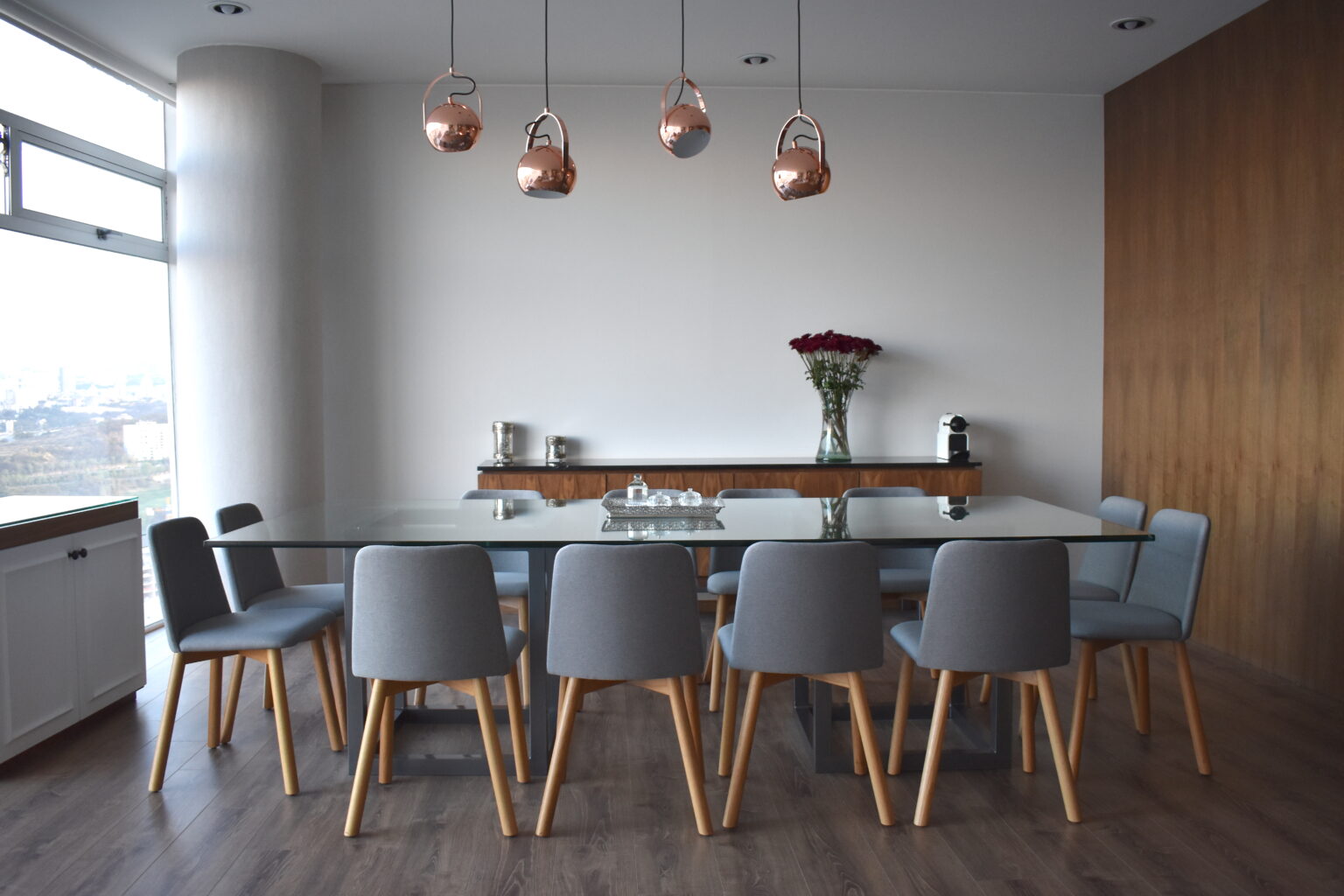 Comedor con mesa de cristal, diez sillas grises y vista panorámica en Lo Alto