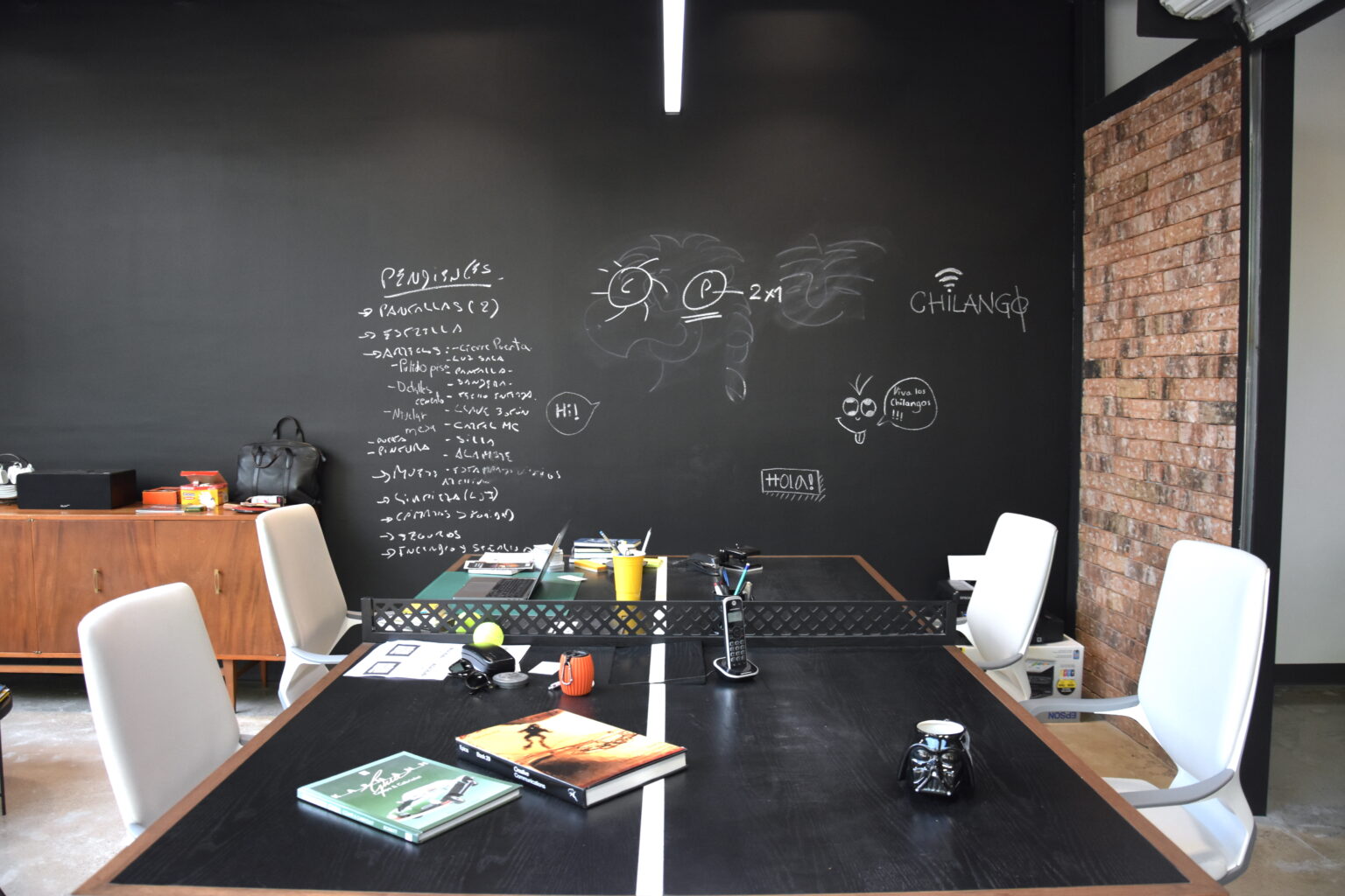 Sala de trabajo con mesas negras, sillas blancas y muro pizarrón en M&C Saatchi