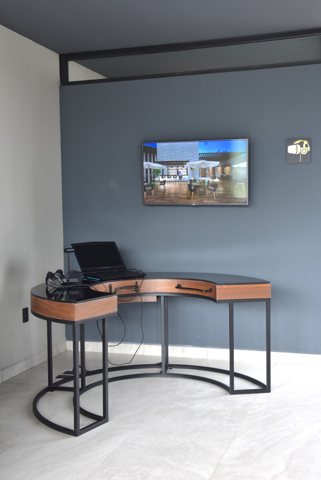 Escritorio curvo de madera y metal bajo pantalla en el showroom Real de Monteza