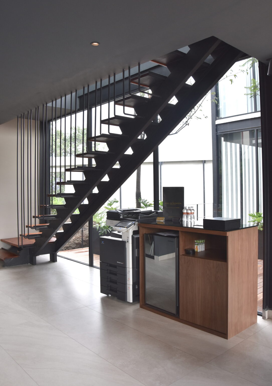 Mueble de apoyo con impresora y frigobar bajo escalera metálica en Real de Monteza