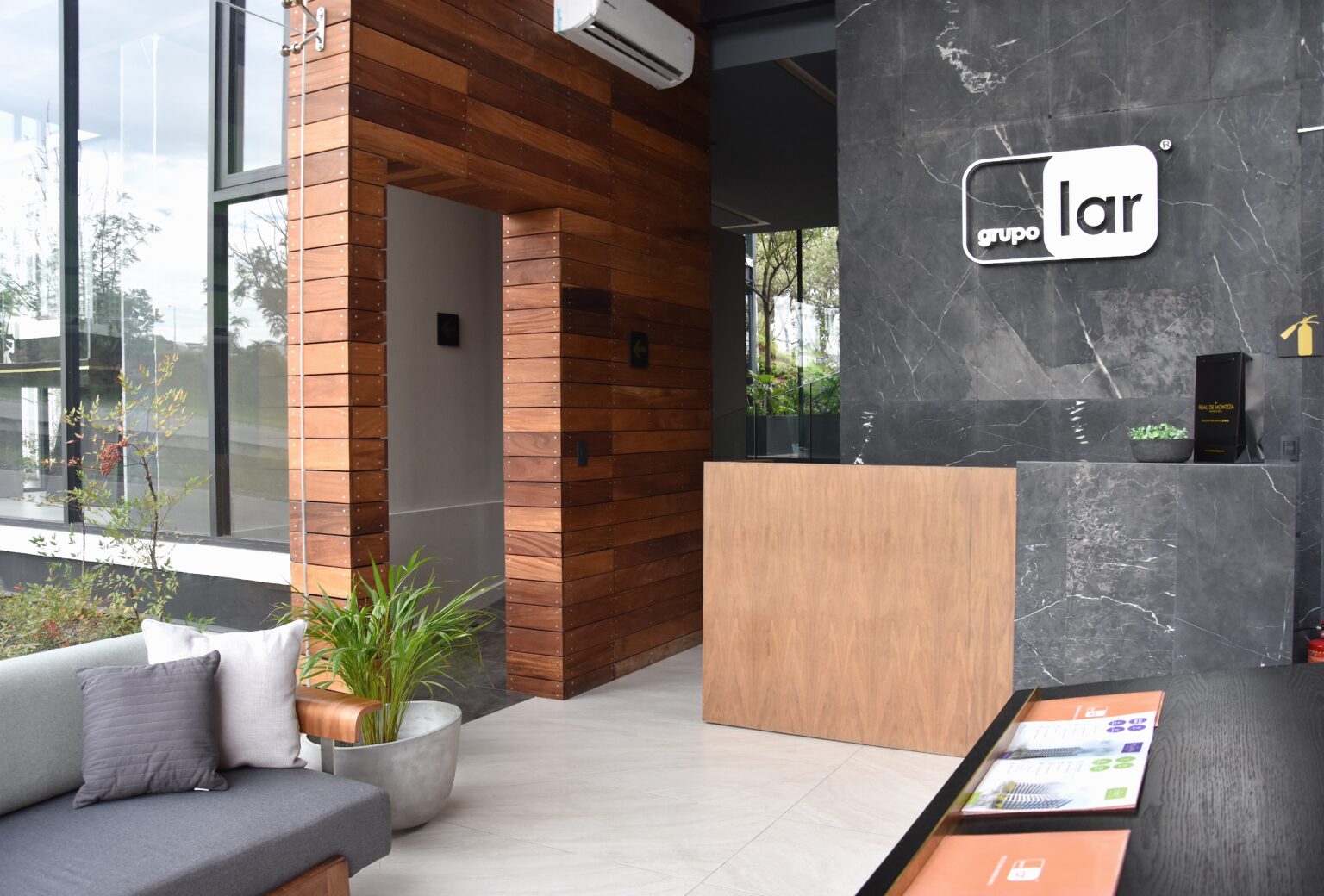Recepción de Grupo Lar en el showroom Real de Monteza con madera y mármol oscuro
