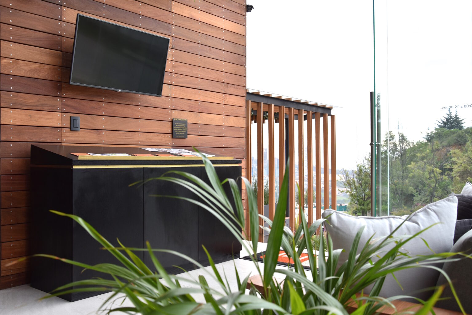 Sala de espera del showroom Real de Monteza con mueble negro, pantalla y muro de madera