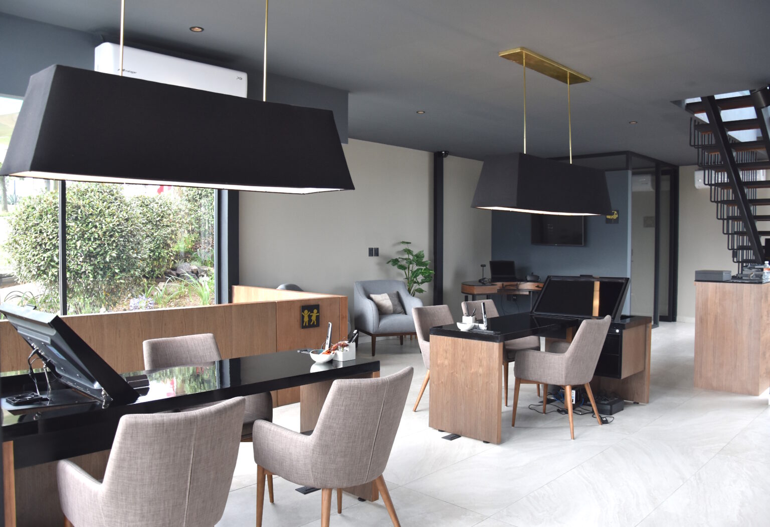 Estaciones de atención del showroom Real de Monteza con escritorios de madera y lámparas negras