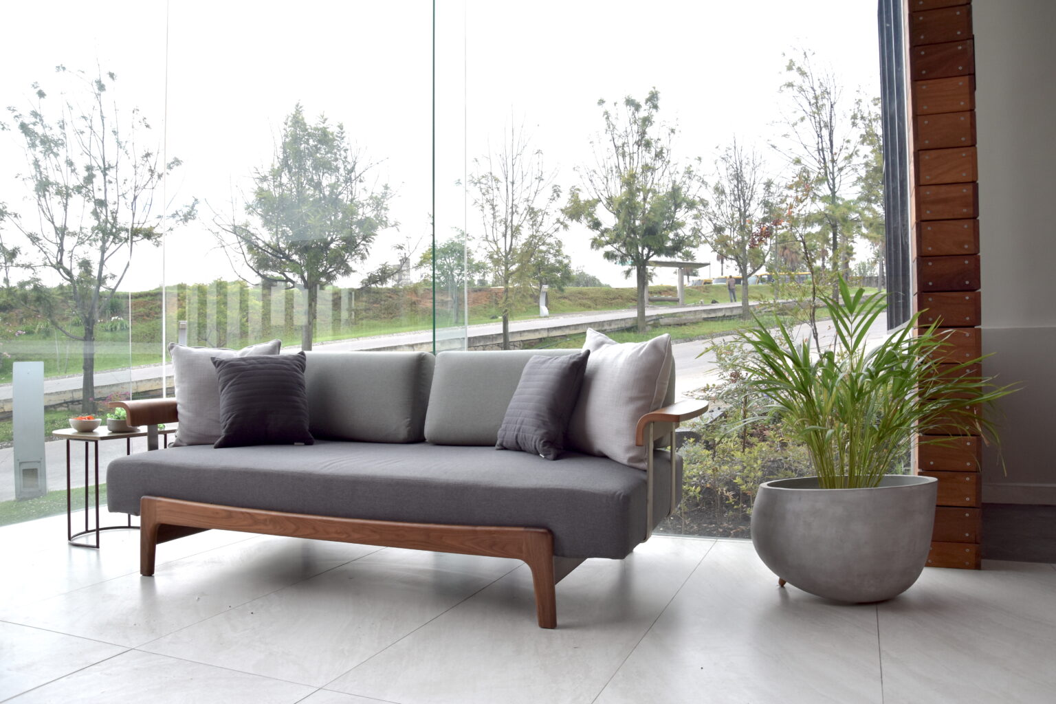 Sofá gris de madera frente al ventanal del showroom Real de Monteza