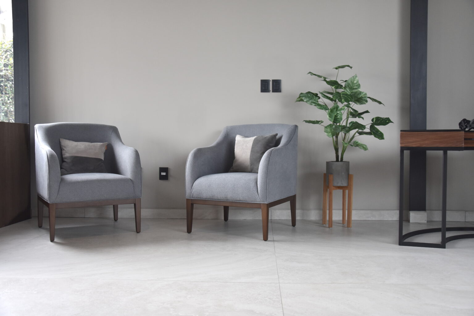 Dos sillones grises con base de madera en la recepción de Real de Monteza