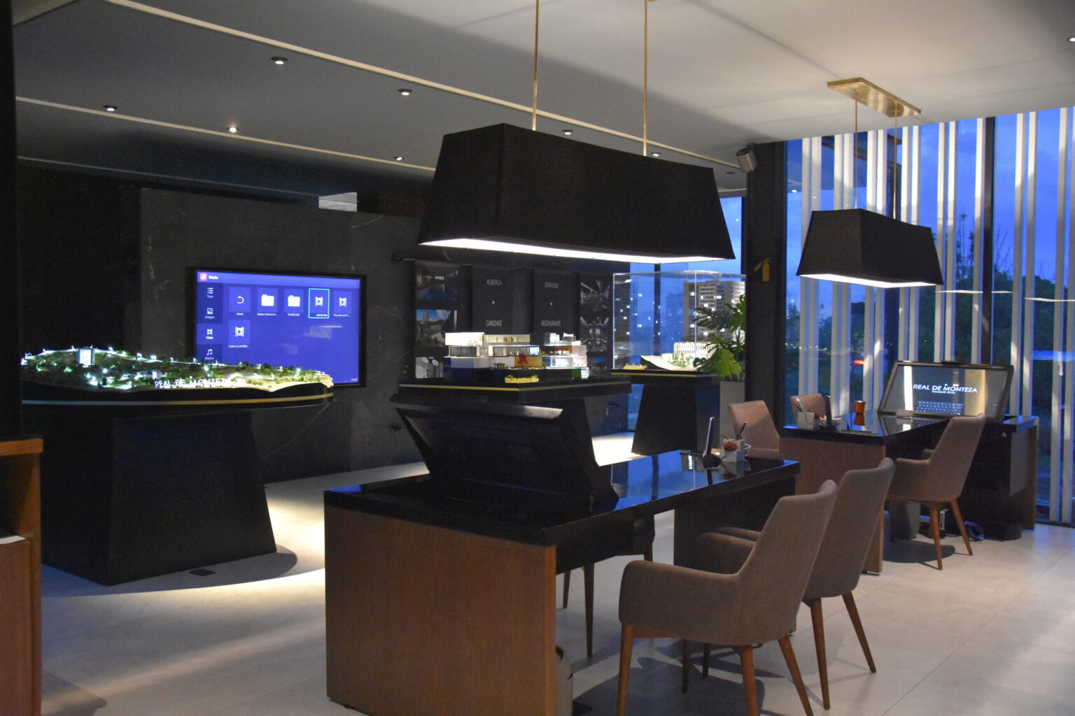 Showroom Real de Monteza iluminado con maquetas, pantallas y estaciones de atención