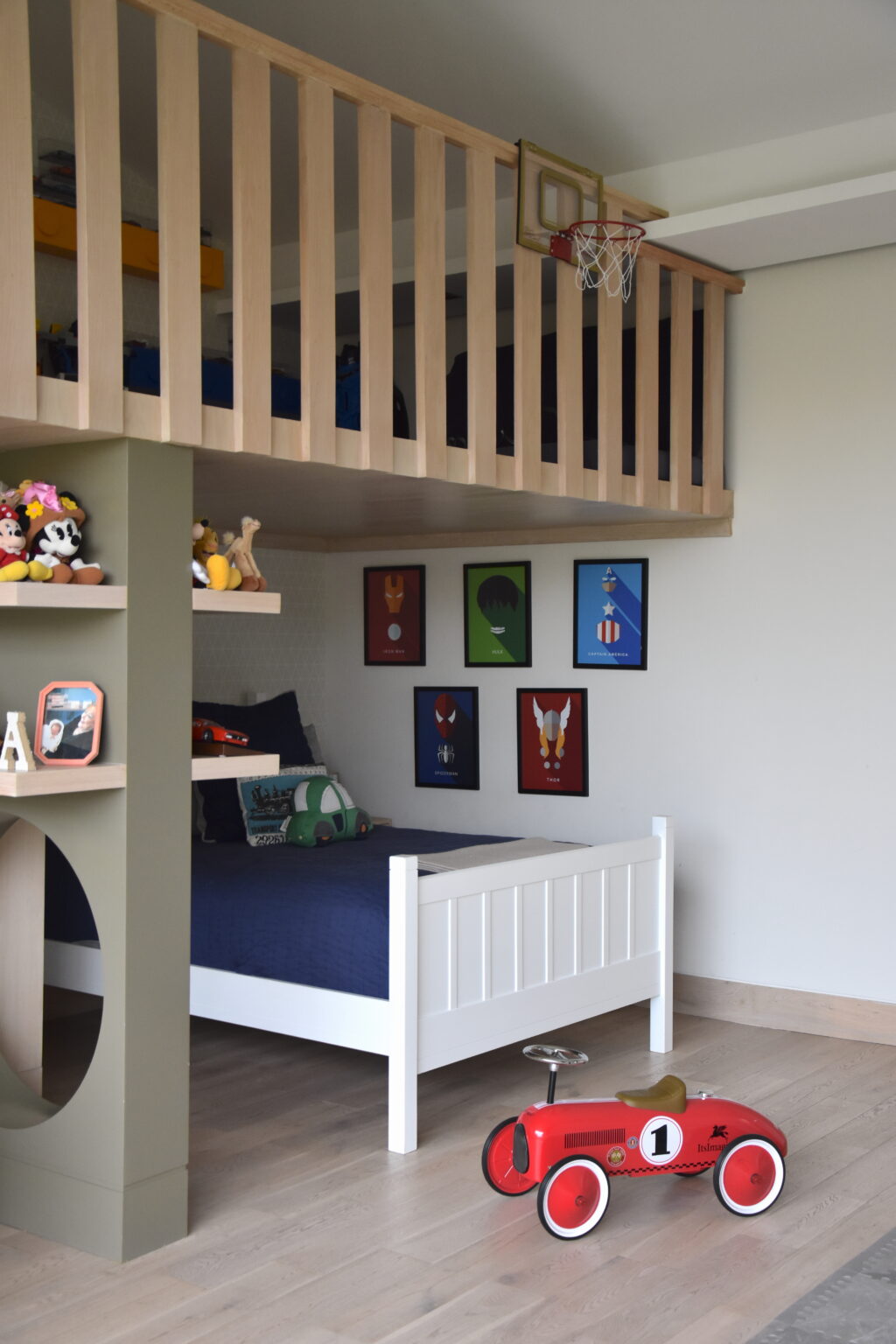 Cama infantil bajo tapanco con ilustraciones deportivas y auto rojo