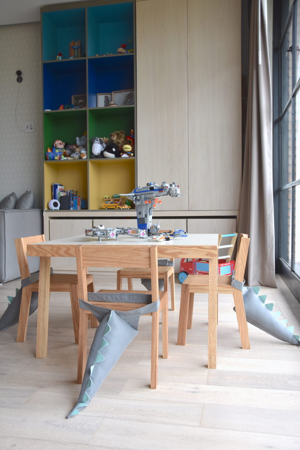 Mesa infantil de madera frente a mueble de almacenamiento de colores