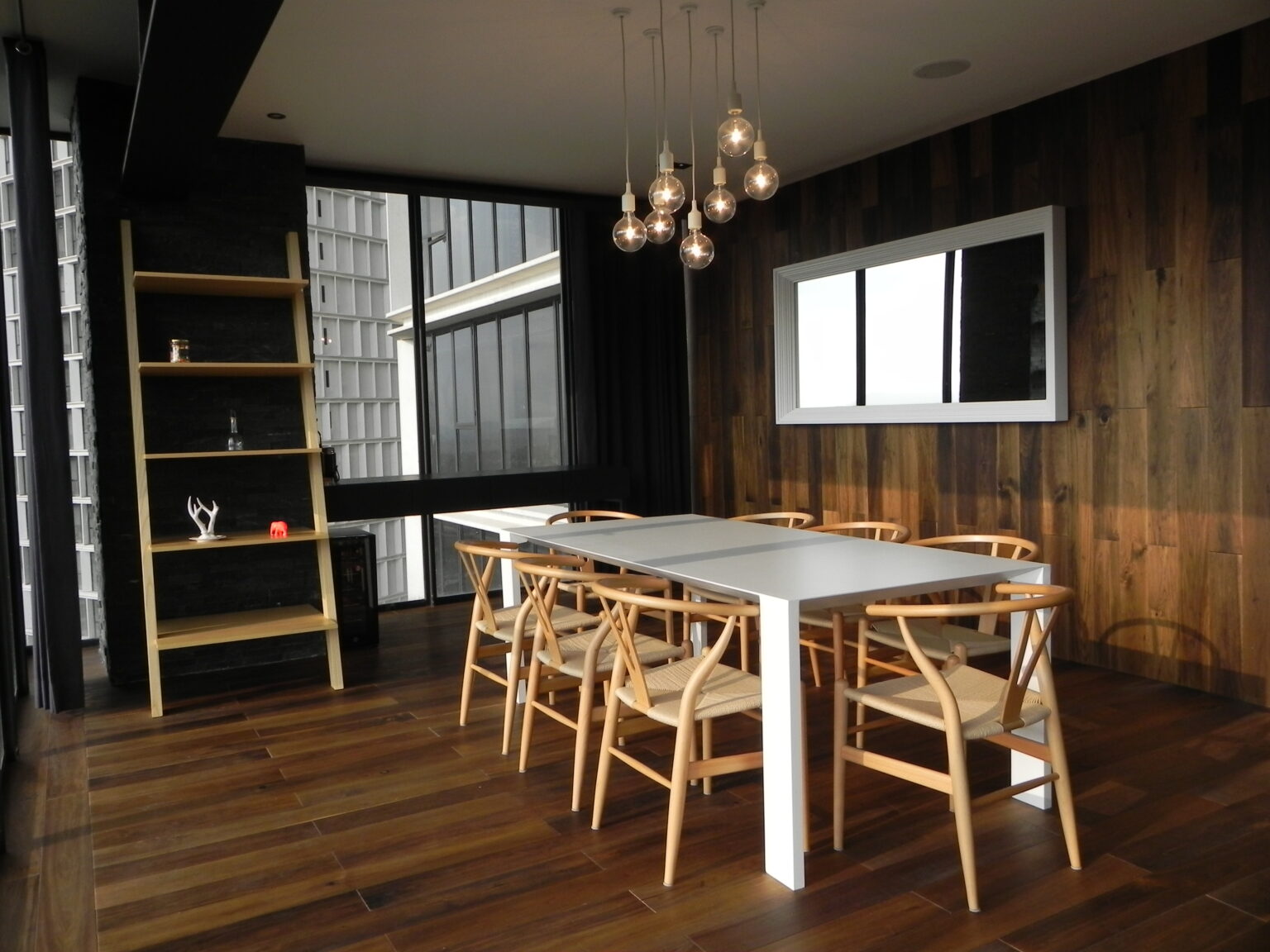 Comedor de Avivia con mesa blanca, sillas de madera y muro revestido en nogal