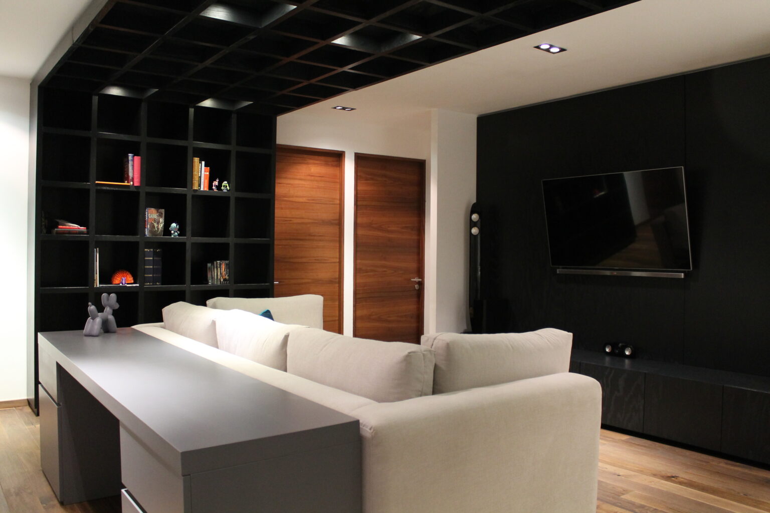 Mueble multimedia negro con televisión y librero en la sala de Avivia