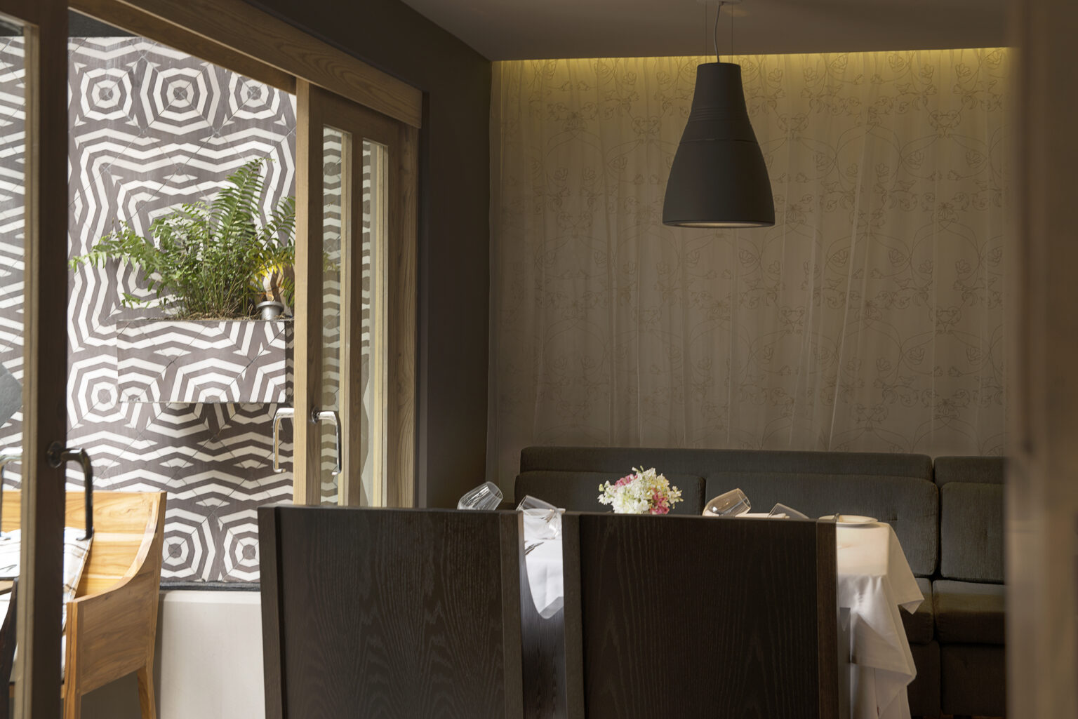 Rincón de comedor de Bresca con banca tapizada, muro ilustrado y lámpara negra