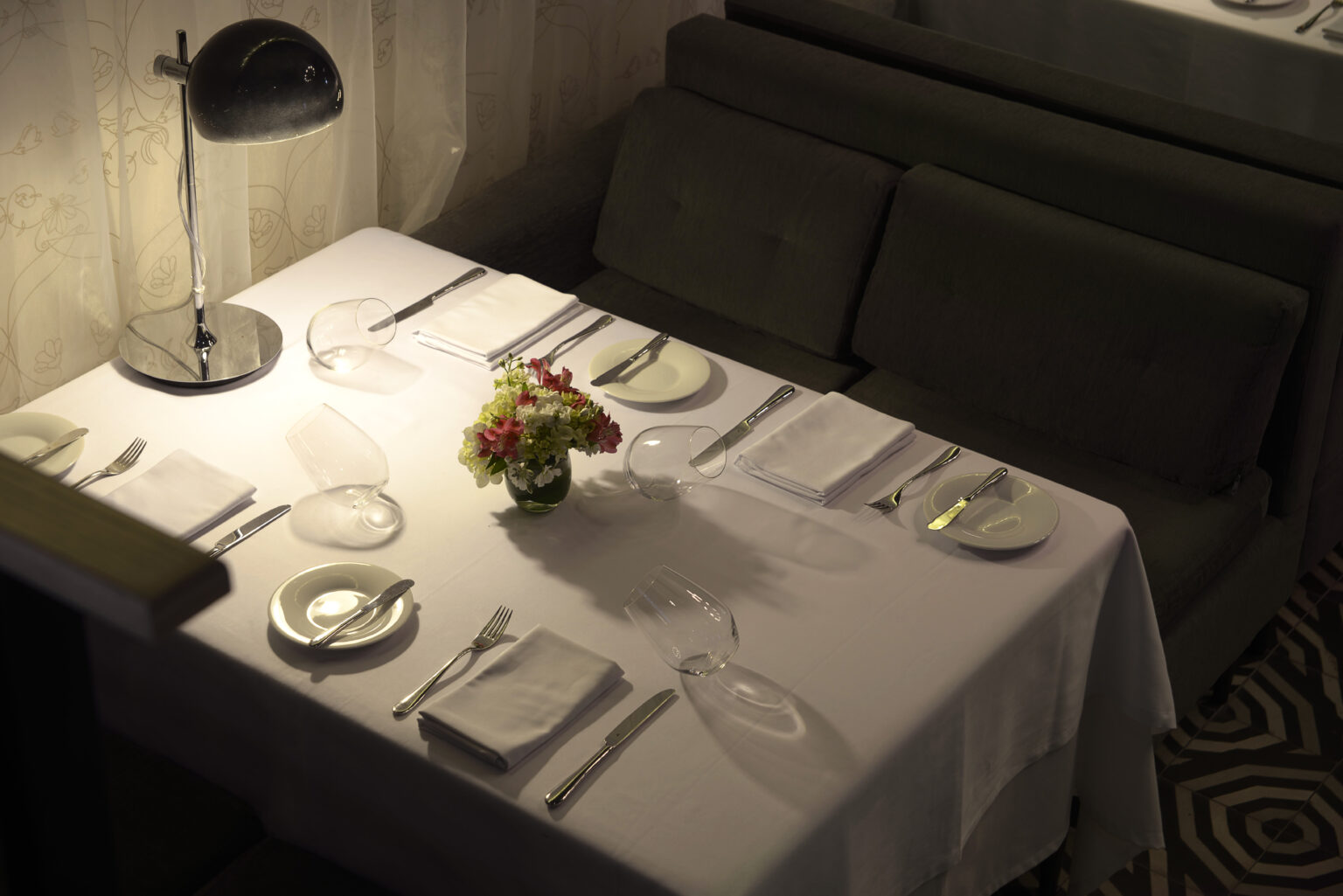 Mesa vestida para cuatro personas en Bresca con lámpara de sobremesa y flores