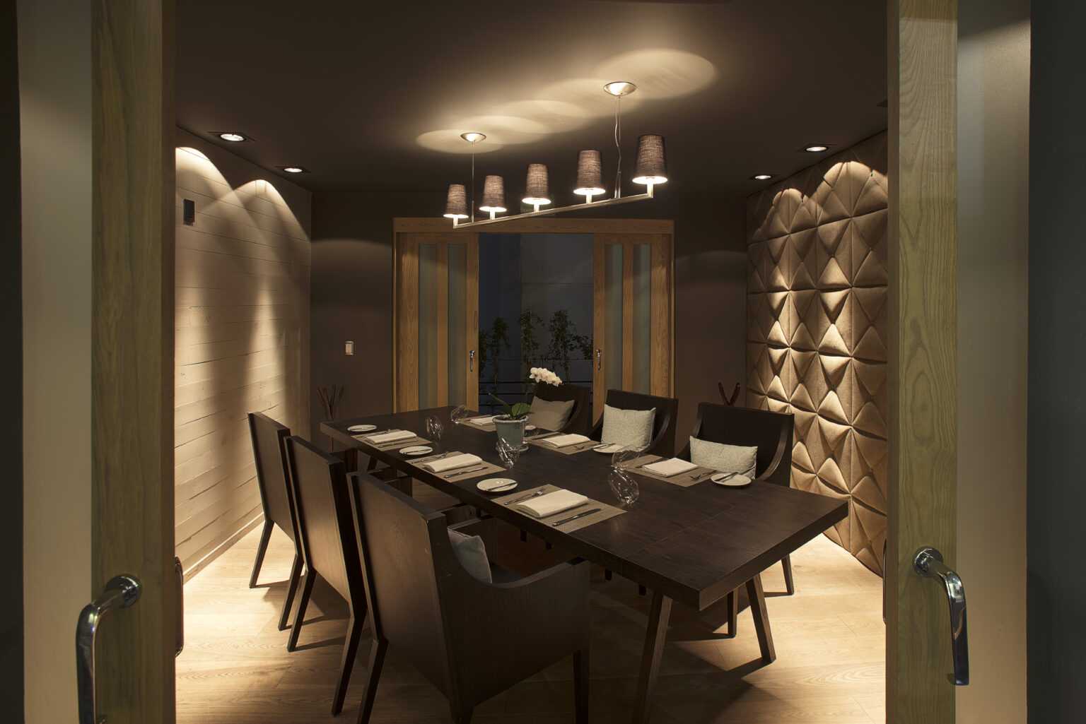 Comedor privado de Bresca con mesa de madera y muro acolchado geométrico