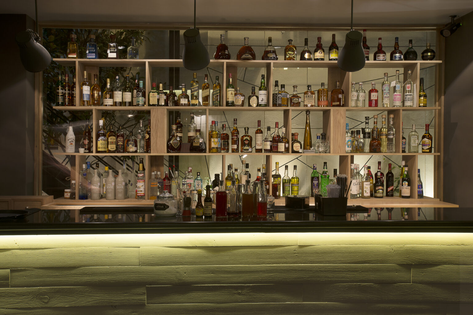 Bar de Bresca con exhibidor de botellas iluminado y frente geométrico