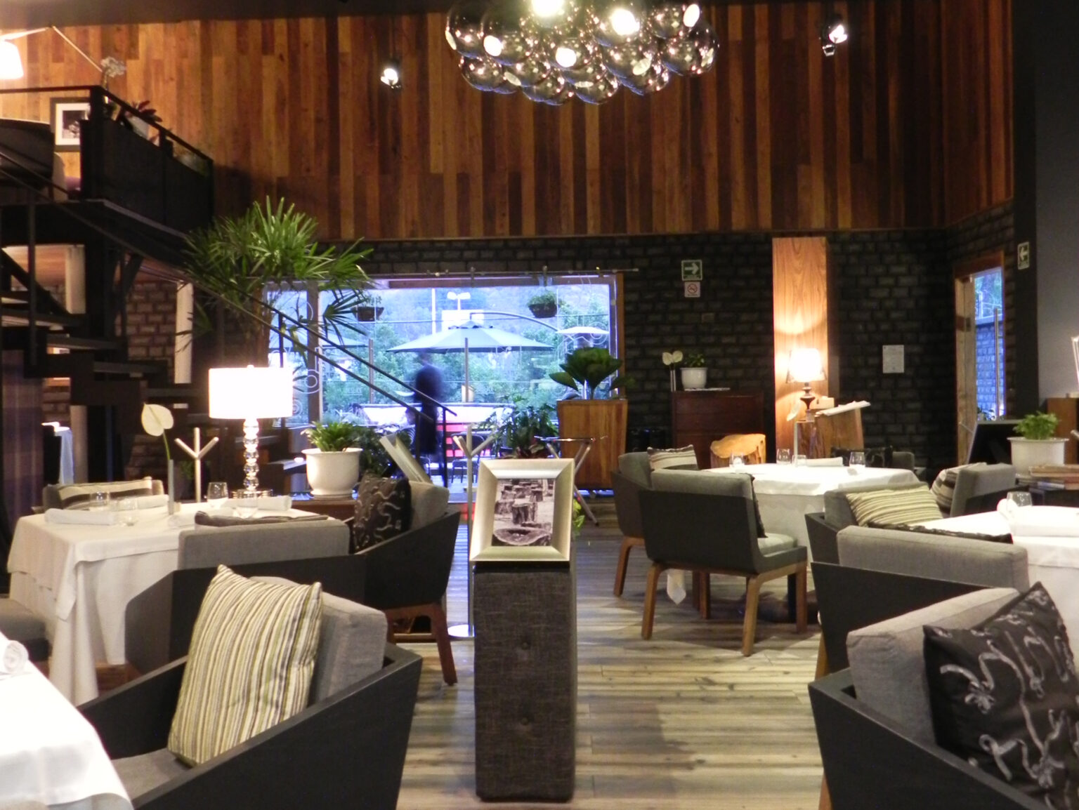 Comedor interior de Raíz con mesas vestidas, sillas tapizadas y salida a la terraza