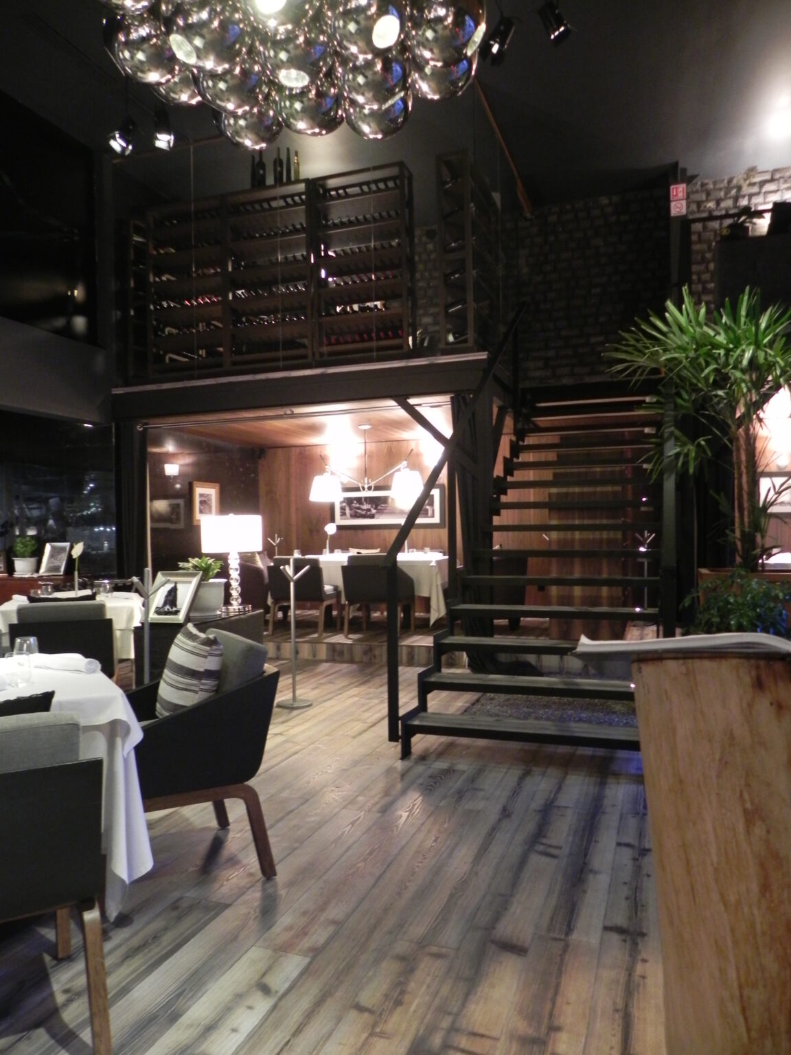 Escalera metálica hacia mezzanine con cava y comedor del restaurante Raíz