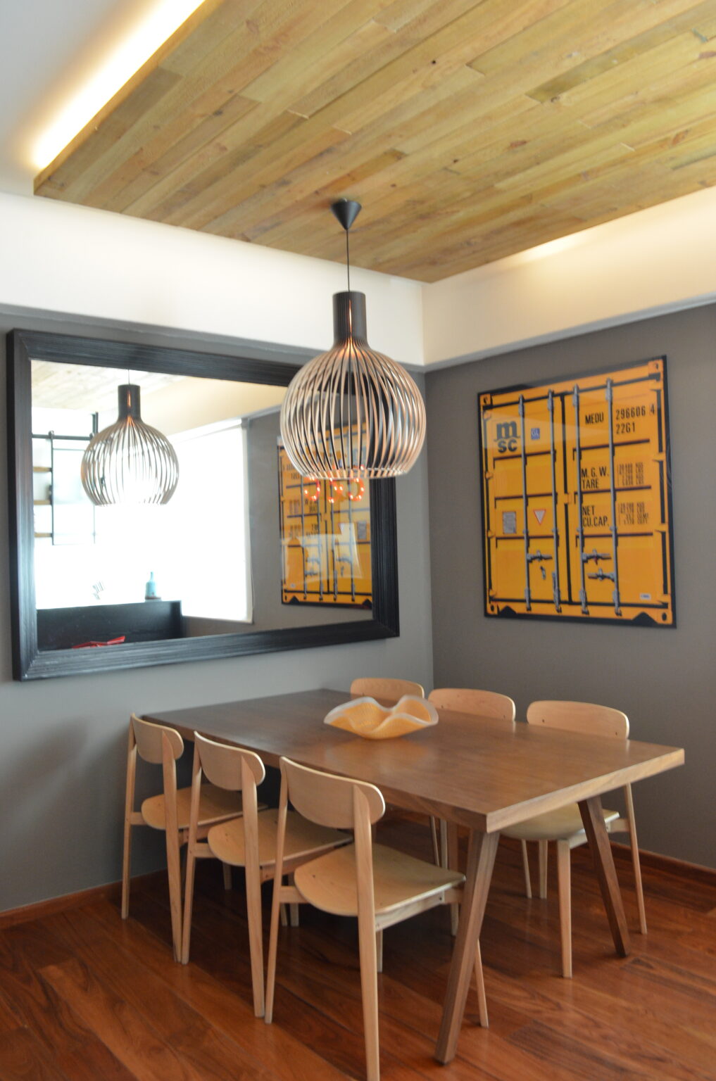 Comedor con mesa de madera, seis sillas, espejo negro y lámpara de varillas