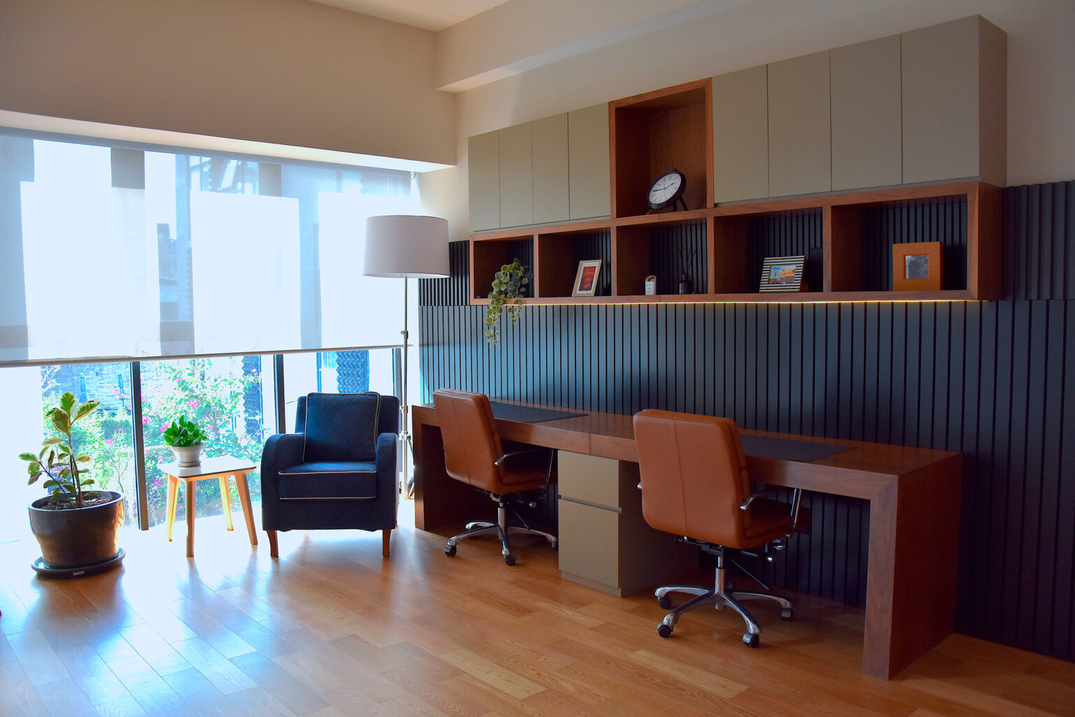 Estudio con escritorio doble, sillas de piel y muro de listones negros en Casa Roma