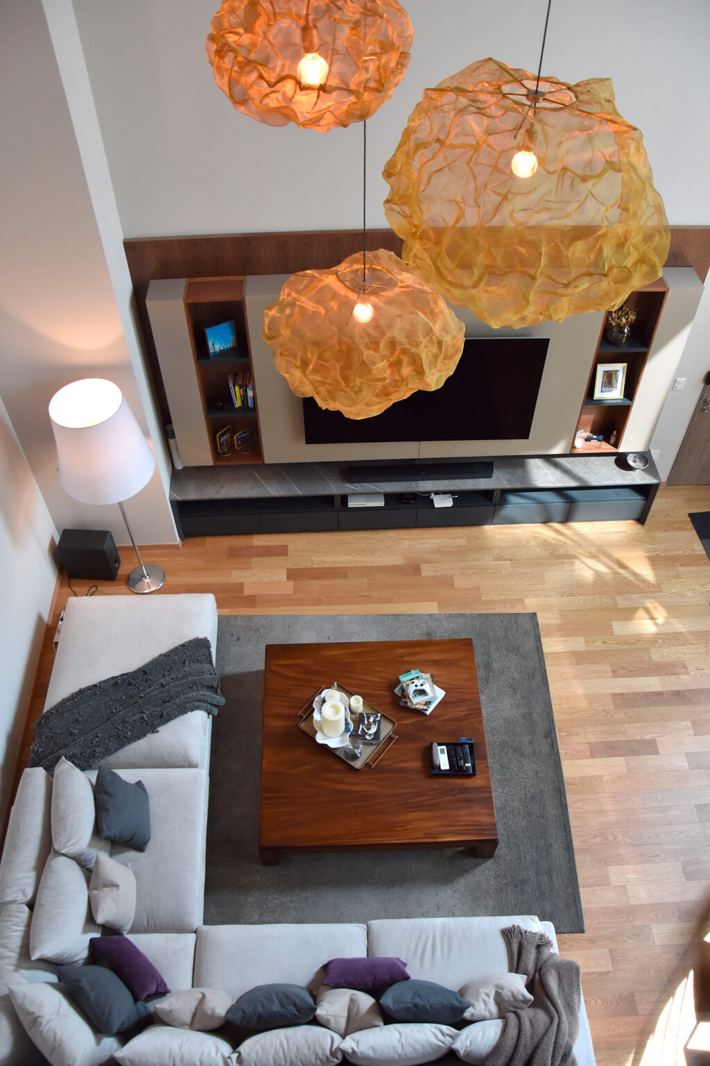 Vista superior de sala con sofá blanco, mesa de madera y lámparas escultóricas