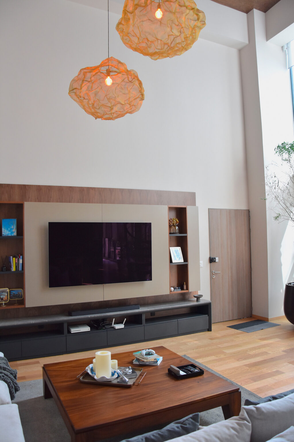 Sala con mueble de televisión y lámparas escultóricas en el volumen de doble altura